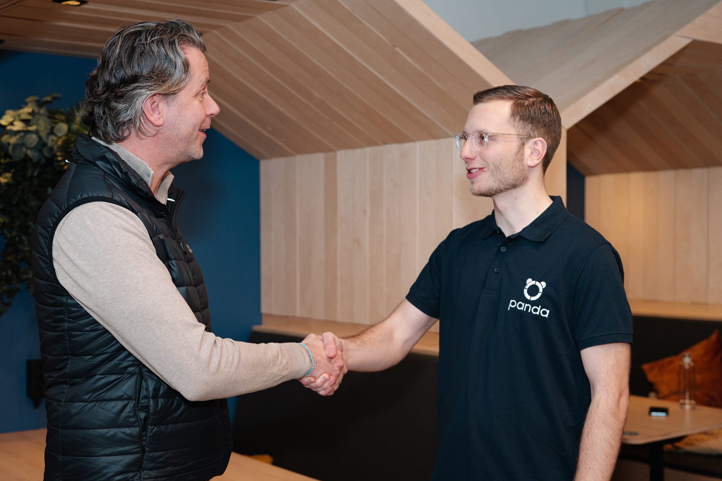Handenschudden in een houten kantoor-omgeving — eerste kennismaking met Panda-adviseur