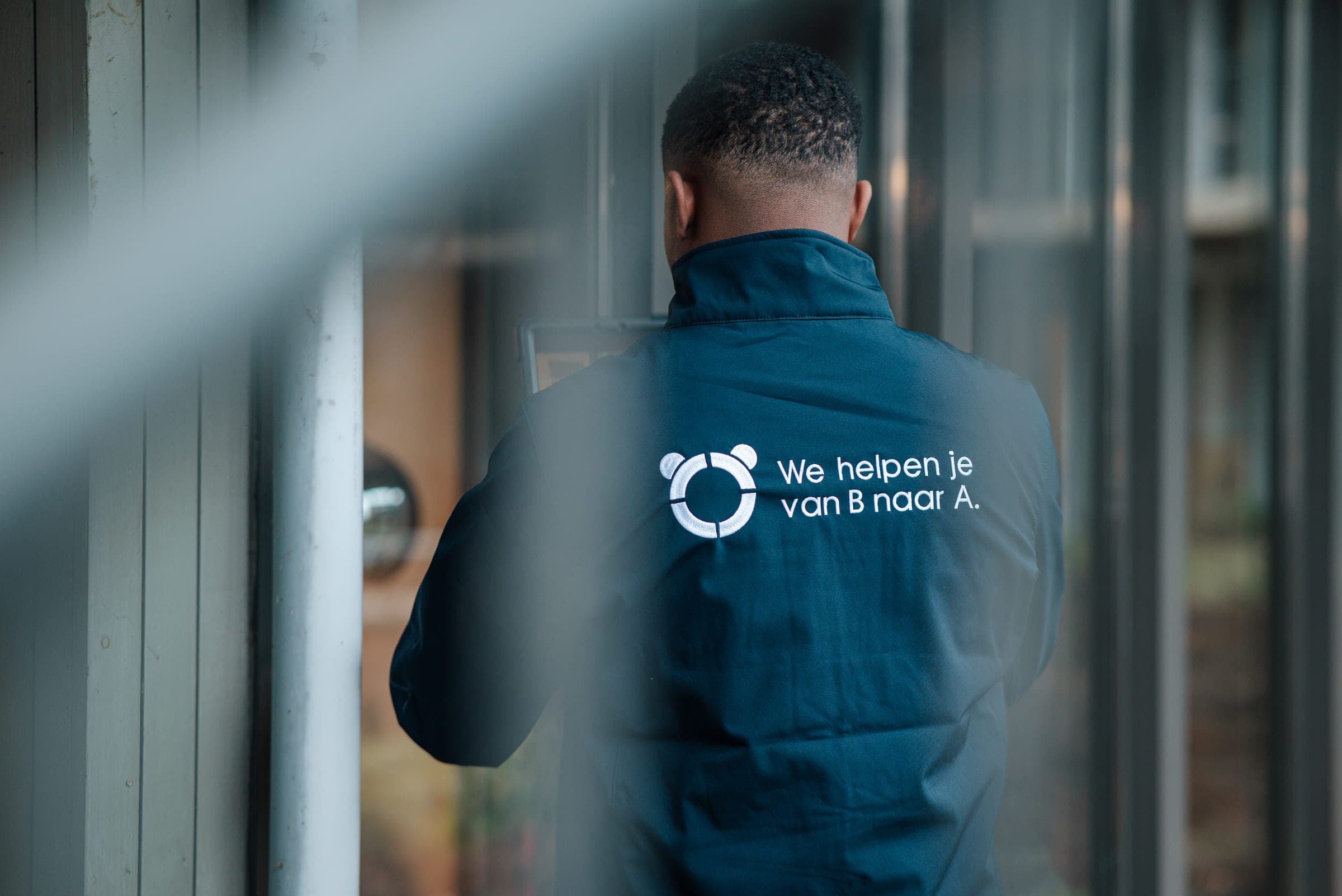 Close-up van een Panda-rugjasje met de slogan 'We helpen je van B naar A'