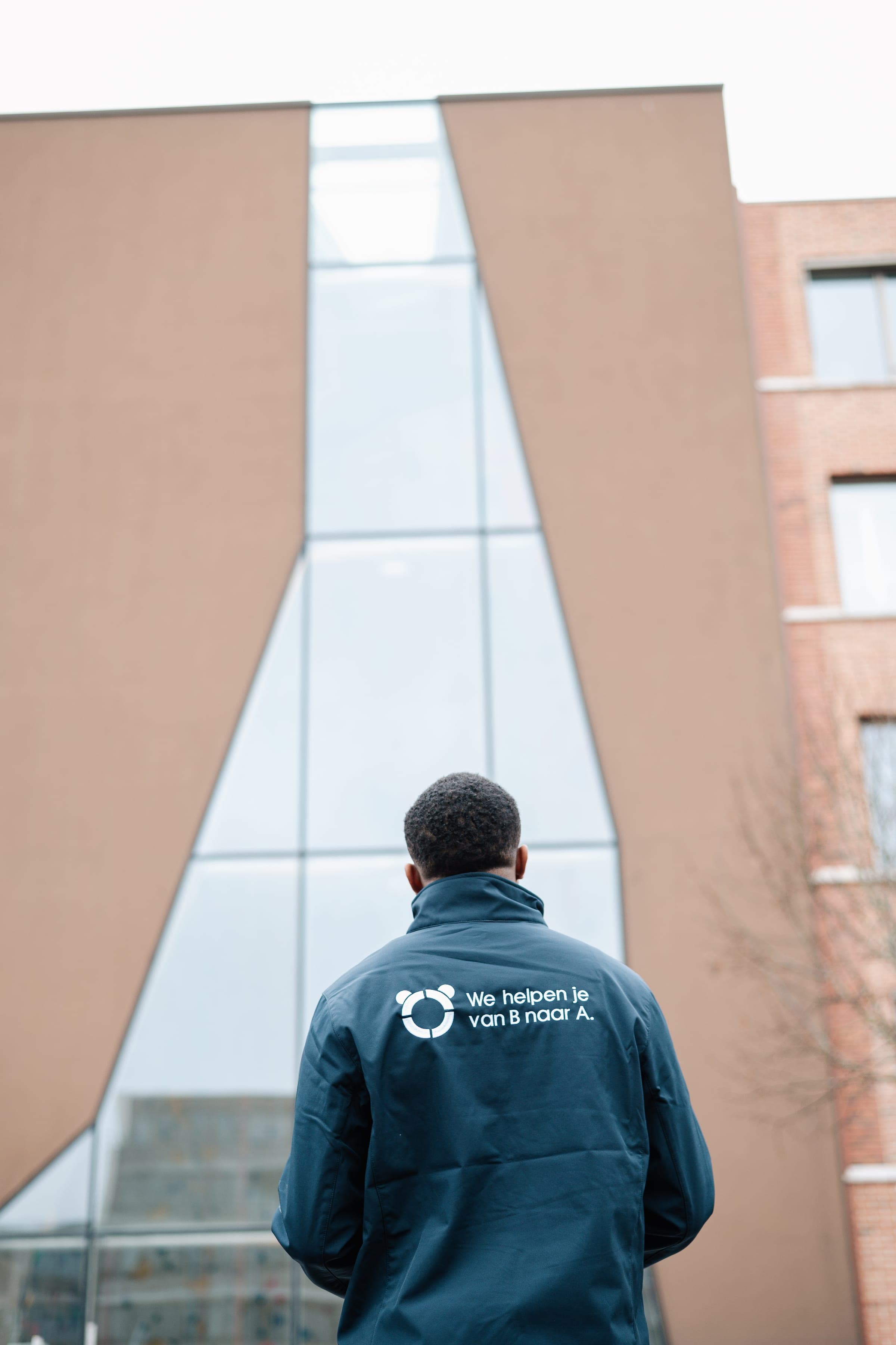 Panda-adviseur kijkt omhoog naar een markant A-vormig glazen kantoorgebouw — beeldmerk voor de portefeuille-aanpak van Panda